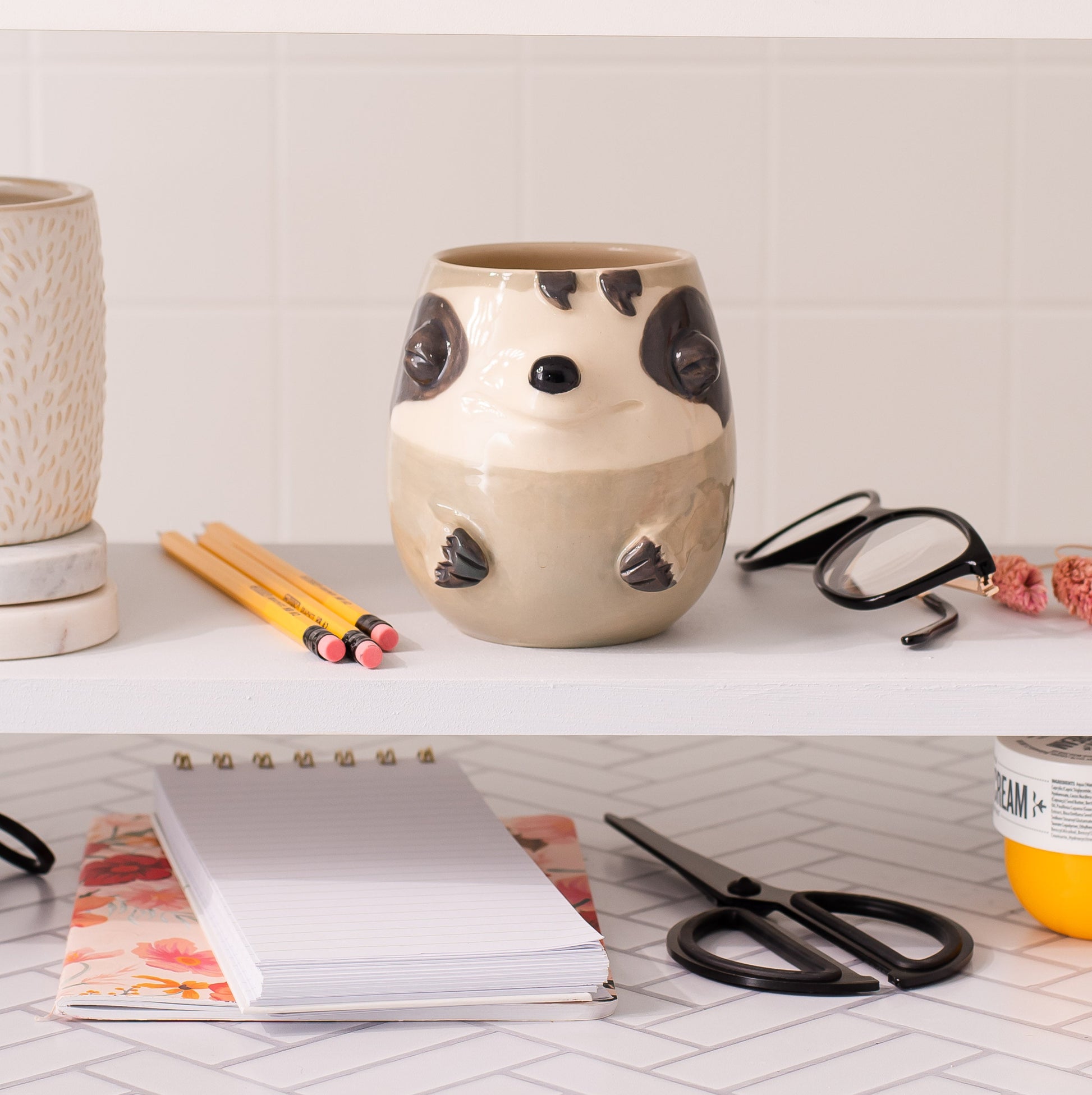Ceramic sloth-shaped container on a shelf with stationery items