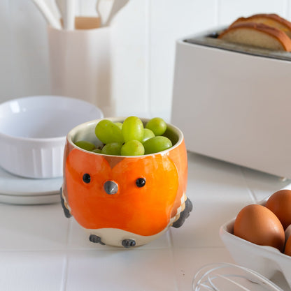 Sculpted robin  bowl with green grapes on a kitchen counter.
